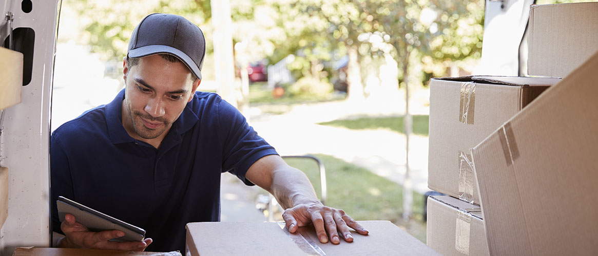 Delivery driver safely checking the weight of a package in the back of his van