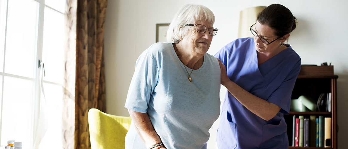 Home health worker helping an elderly resident to stand up