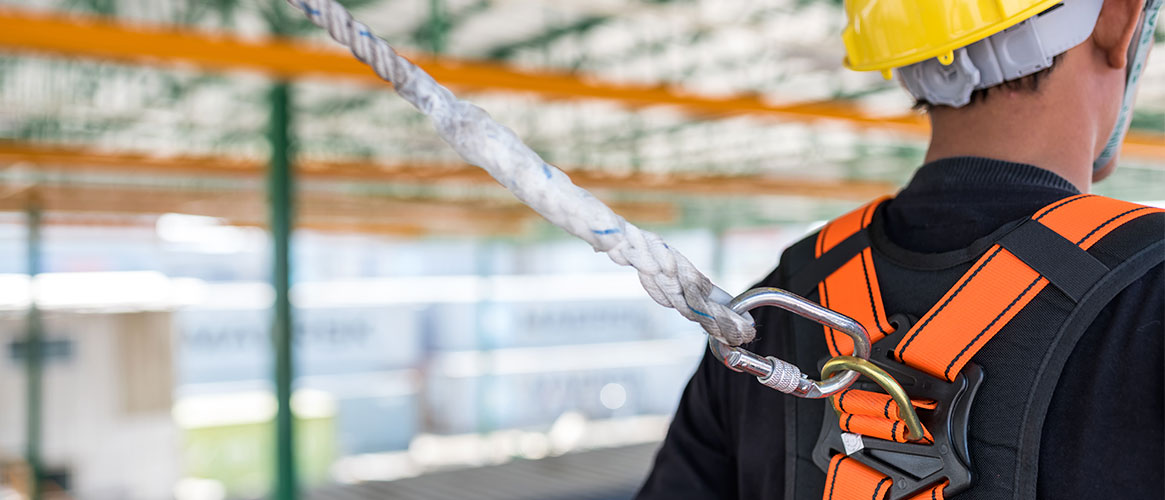 Construction worker wearing safety harness and safety line while working from heights.