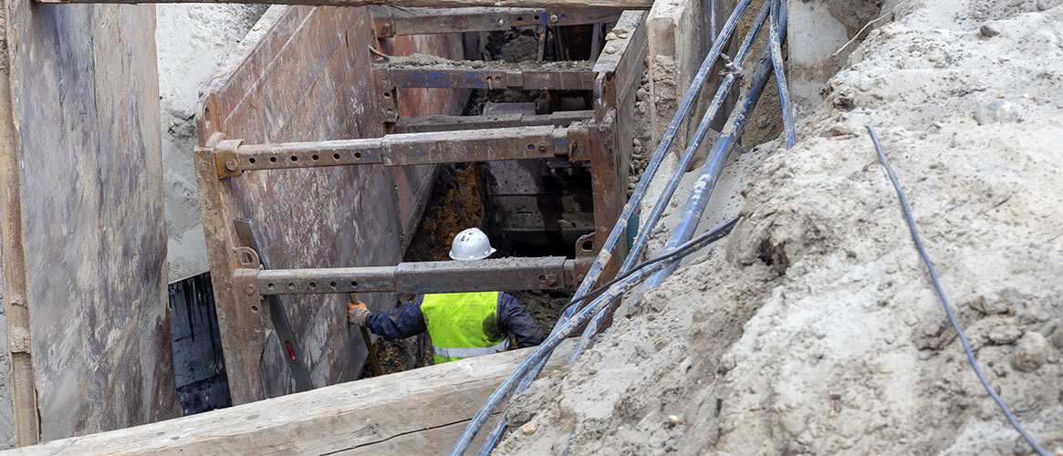 Worker inside trench fortified with a shoring system to guard against a cave-in.