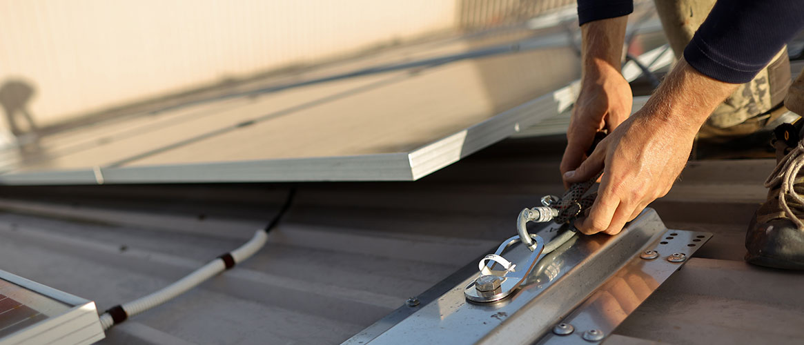 Roofing worker connecting fall protection rope to an anchor point
