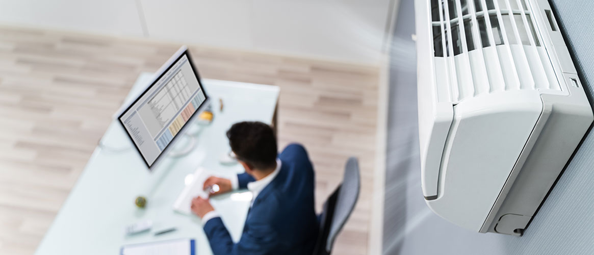 Worker at his desk in an office with a ventilation system helping improve indoor air quality
