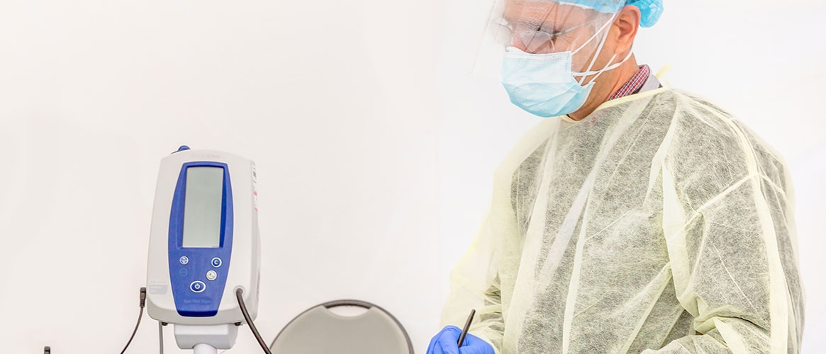 Medical provider using contact precautions including gown, gloves, face shield, and head covering.