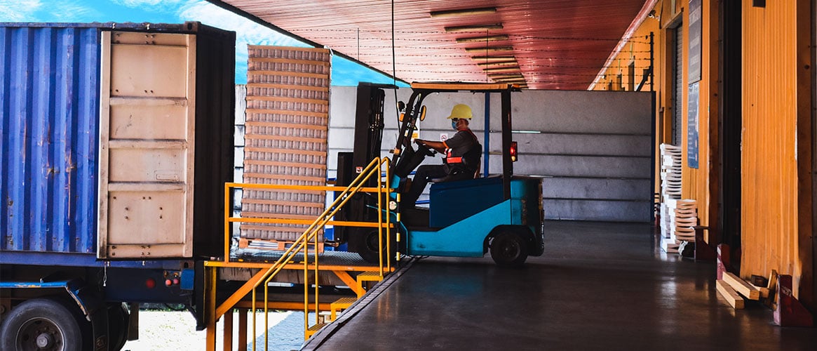 Forklift operator loading merchandise onto a trailer for delivery.