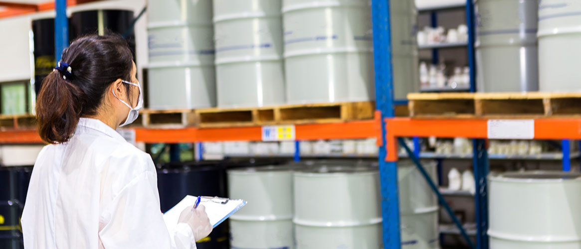 Worker reviewing Safety Data Sheets for hazardous materials in storage