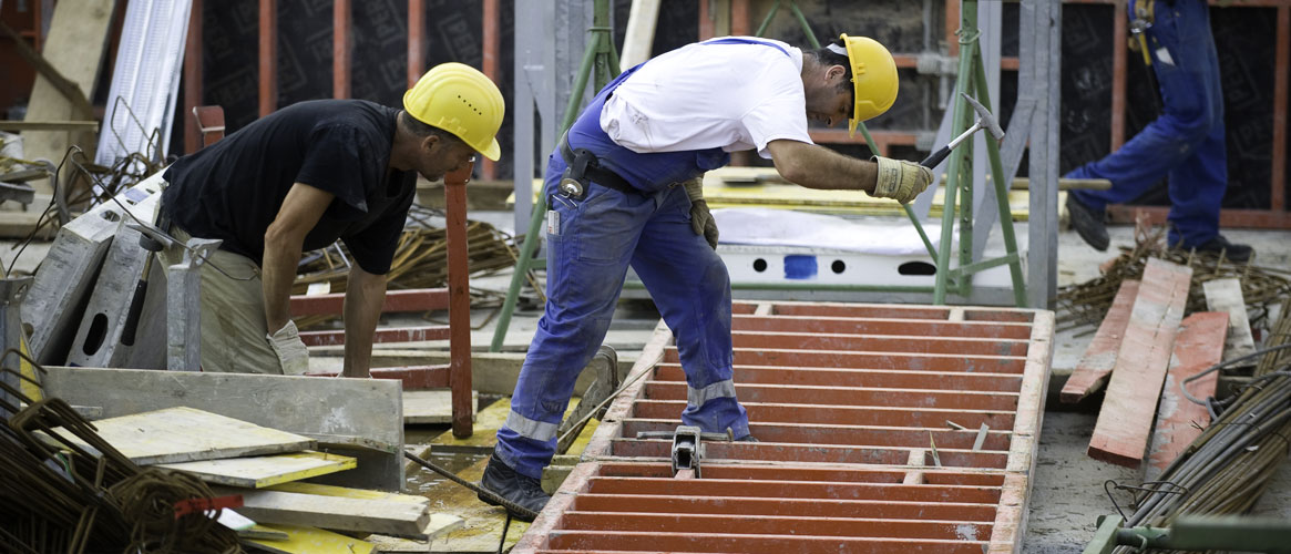 Dangerous job site with piles of debris as two construction workers carefully step through