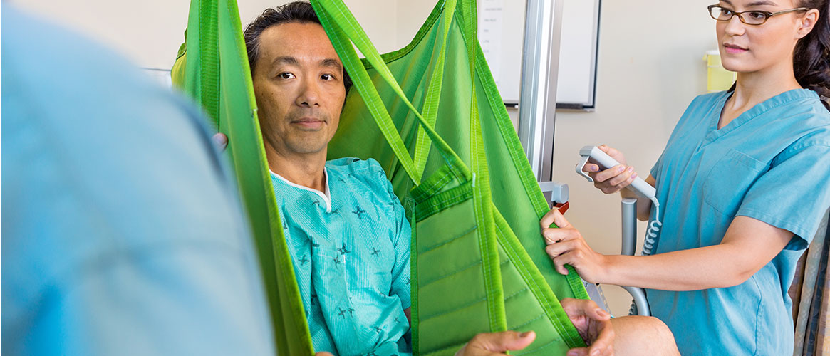 Nurses assisting a patient using a mechanical lift