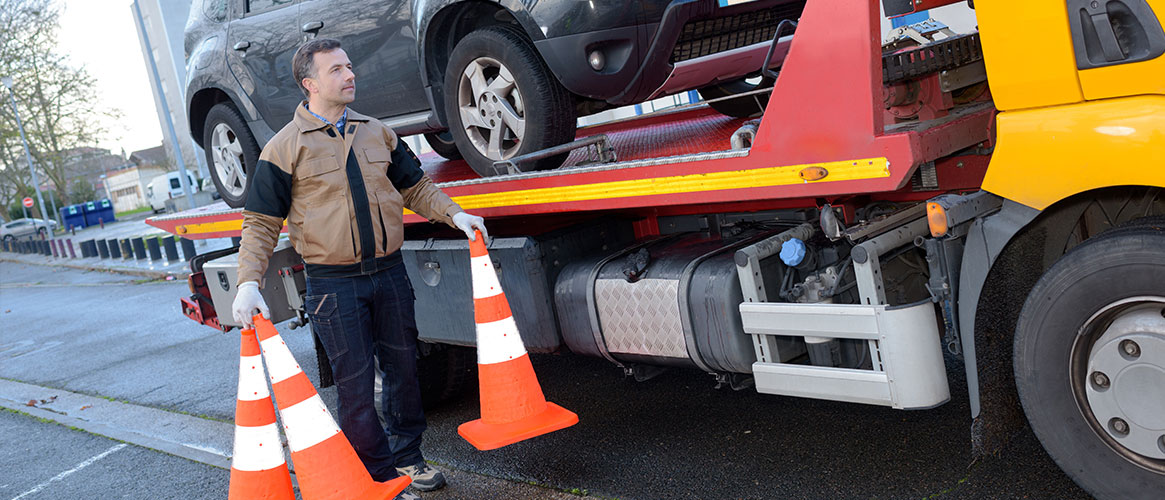 worker using safety cones near tow truck
